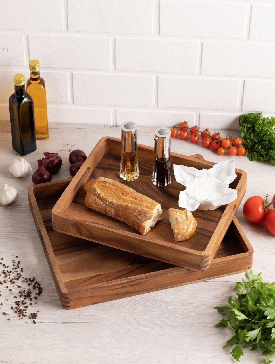 Holztablett-Set in einer Küche, gefüllt mit Baguette, Gewürzflaschen und umgeben von frischen Zutaten, aus der Vogelperspektive.