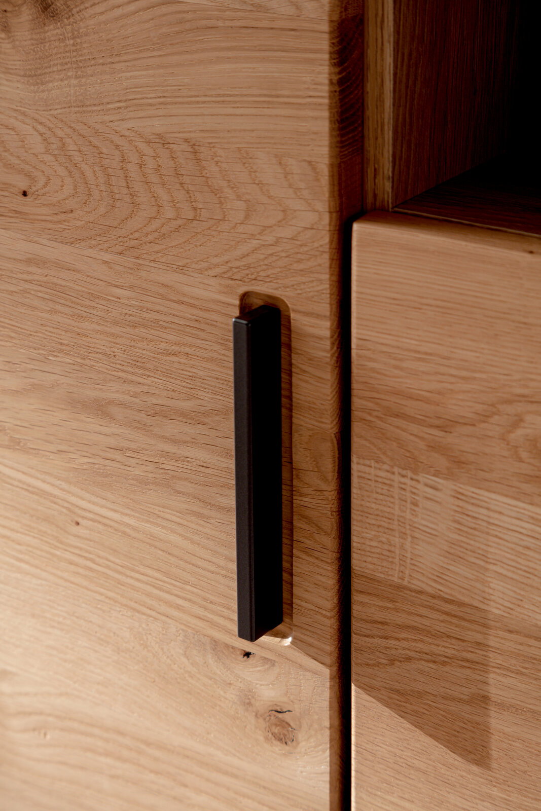 Nahaufnahme eines Highboards aus Holz mit schwarzem Griff, seitliche Perspektive