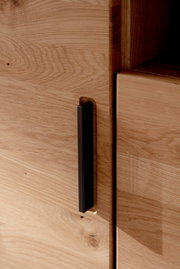 Nahaufnahme eines Highboards aus Holz mit schwarzem Griff, seitliche Perspektive