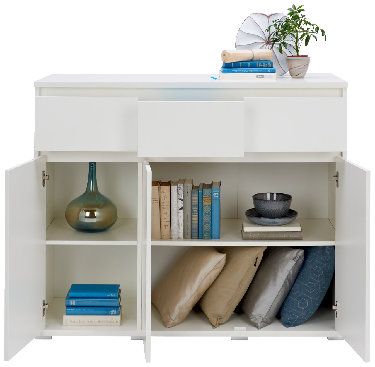Weißes Sideboard mit zwei offenen Türen, gefüllt mit Büchern, Kissen und Dekorationen, aus frontaler Perspektive.