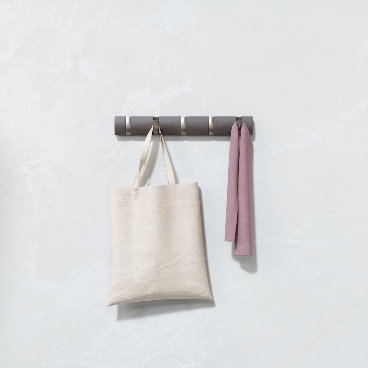 Wandgarderobe mit mehreren Haken, an denen eine beige Tasche und ein rosa Tuch hängen, seitliche Perspektive
