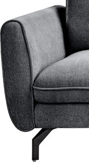 Detailaufnahme eines grauen Polstersessels mit abgerundeter Armlehne, Sitzkissen und schwarzem Metallfuß, seitliche Perspektive