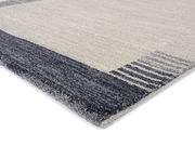 Frisé-Teppich in Nahaufnahme, perspektivisch von der Seite fotografiert, mit grauen und beigen Streifen.