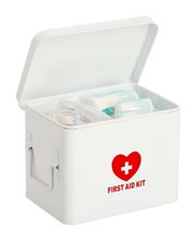 Weiße Medizinbox mit rotem Herz und Kreuz, geöffnet mit sichtbarem Inhalt, aus leicht schräger Perspektive.