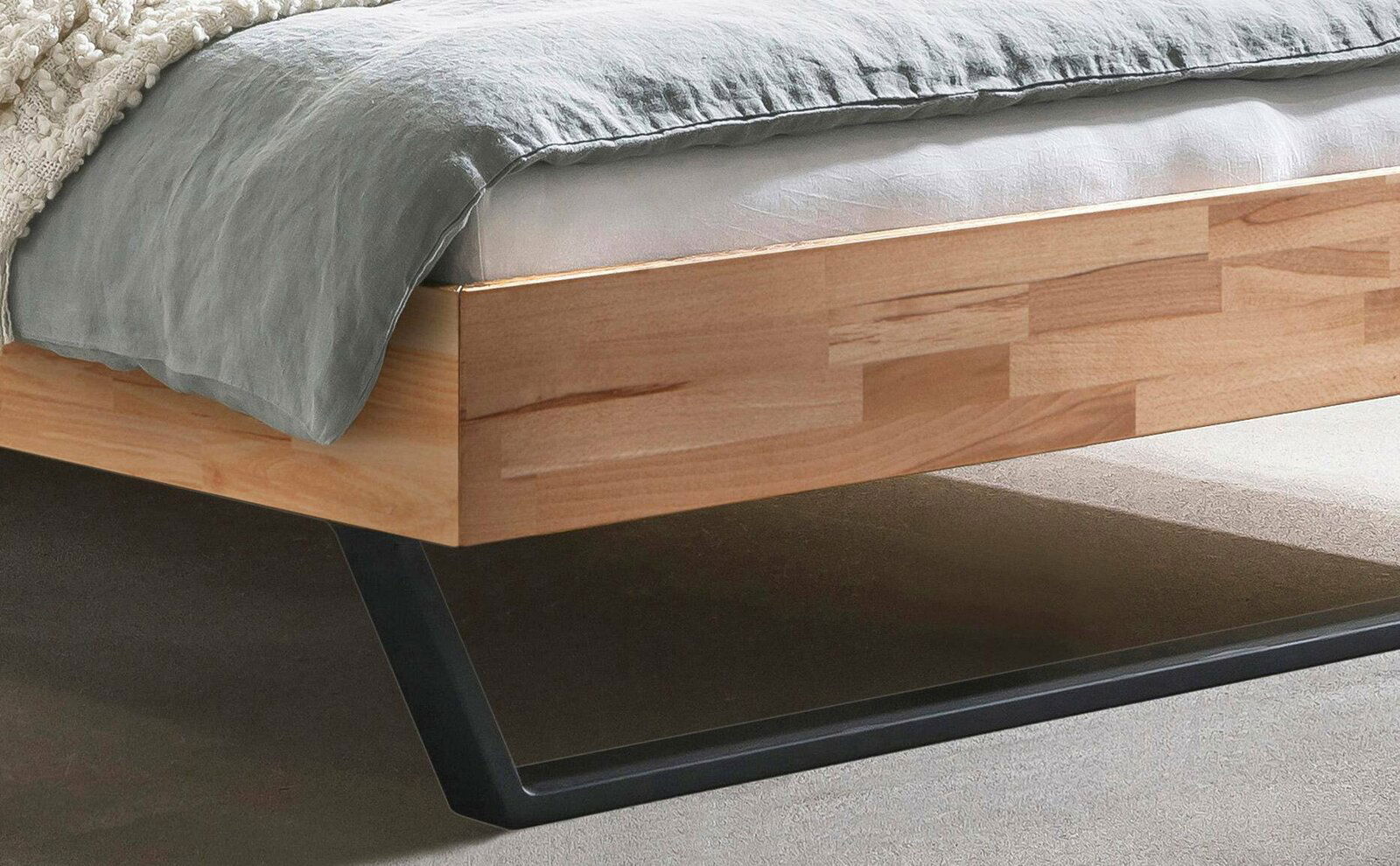 Nahaufnahme eines modernen Bettgestells aus Holz mit Metallbeinen, seitliche Perspektive