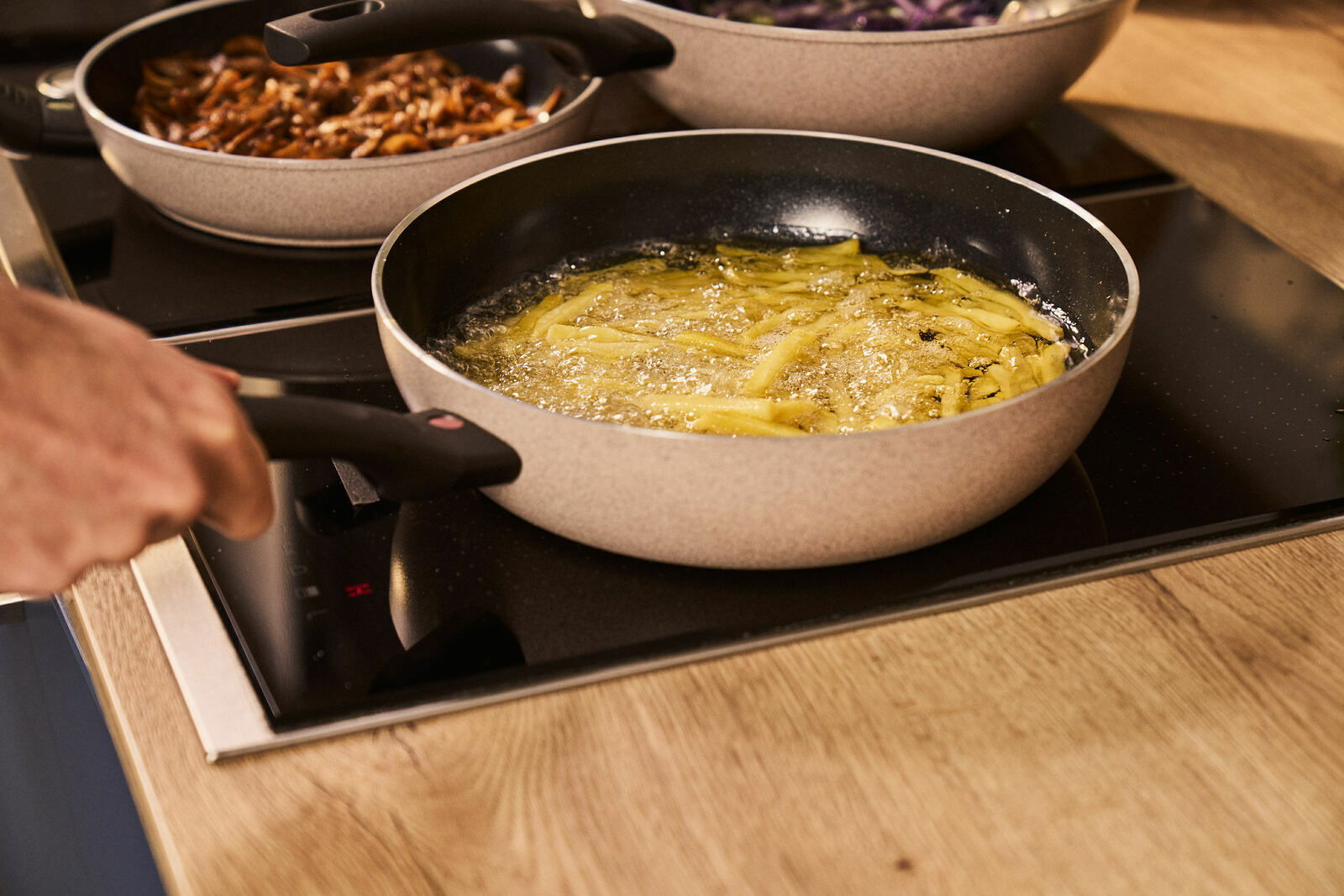 BALLARINI Schmorpfanne LEDRO Schmorpfanne mit 28 cm Durchmesser auf einem Herd, in der Pommes frittieren. Seitliche Perspektive.