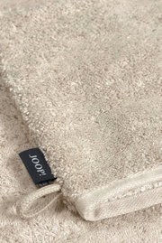 Beige washandje van badstof met zwart Joop-label, close-up