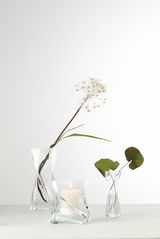 Drei elegante Solifleurvasen Volare aus klarem Glas, in verschiedenen Größen, mit Blumen und einer Kerze dekoriert. Frontalansicht.
