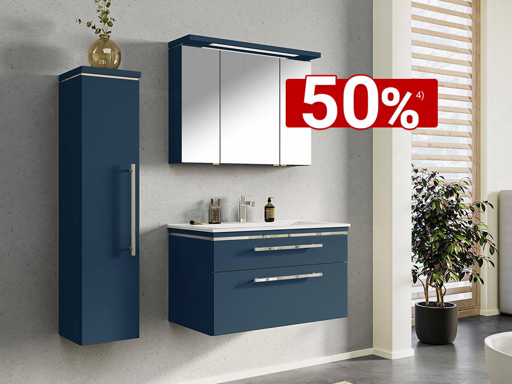 Moderne badkamer met een zwevende badmeubelset in mat donkerblauw, een witte wastafel, een driedeurs spiegelkast met LED-verlichting en een bijpassende hoge kast tegen een wand in lichte betonlook.