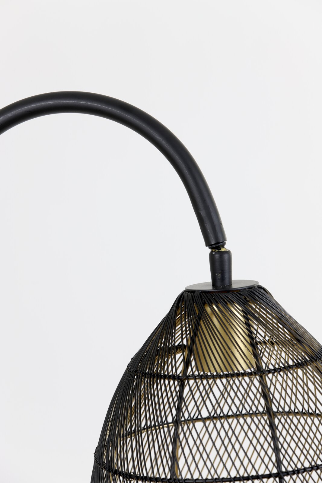 Detailopname in zijaanzicht van een zwarte metalen lamp met gebogen arm, open draadkap en goudkleurig accent