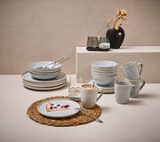 Kombiservice 20-tlg. in eleganter Tischdekoration, bestehend aus Tellern, Schalen und Tassen in sanften Blautönen, seitliche Perspektive.