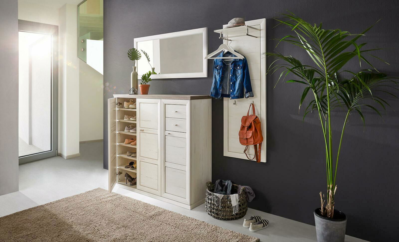 Hom´in Spiegel CAMRON Heller Flur mit einem weißen Schuhschrank und Garderobenpaneel, dekoriert mit Pflanzen und Accessoires, seitliche Perspektive.