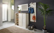 Heller Flur mit einem weißen Schuhschrank und Garderobenpaneel, dekoriert mit Pflanzen und Accessoires, seitliche Perspektive.