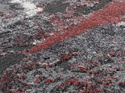 Nahaufnahme eines Designer-Teppichs mit abstraktem Muster in Grau-, Weiß- und Rottönen.