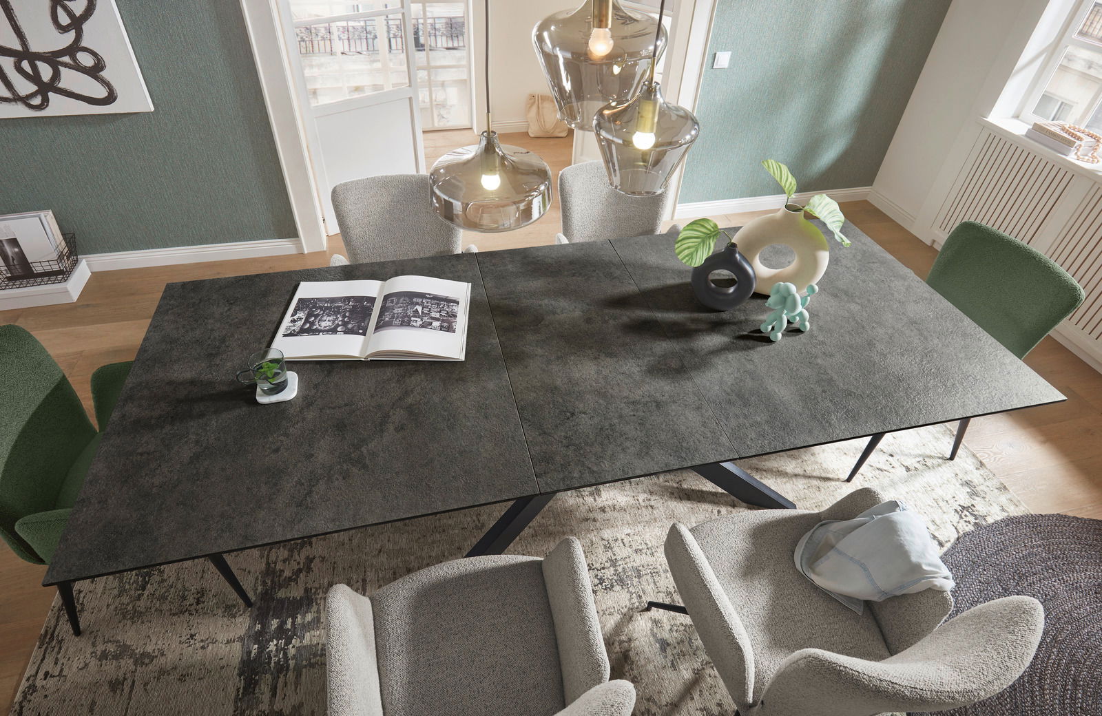 Moderner Esstisch mit dunkler Tischplatte, umgeben von stilvollen Stühlen in einem hellen Raum, aus der Vogelperspektive betrachtet.