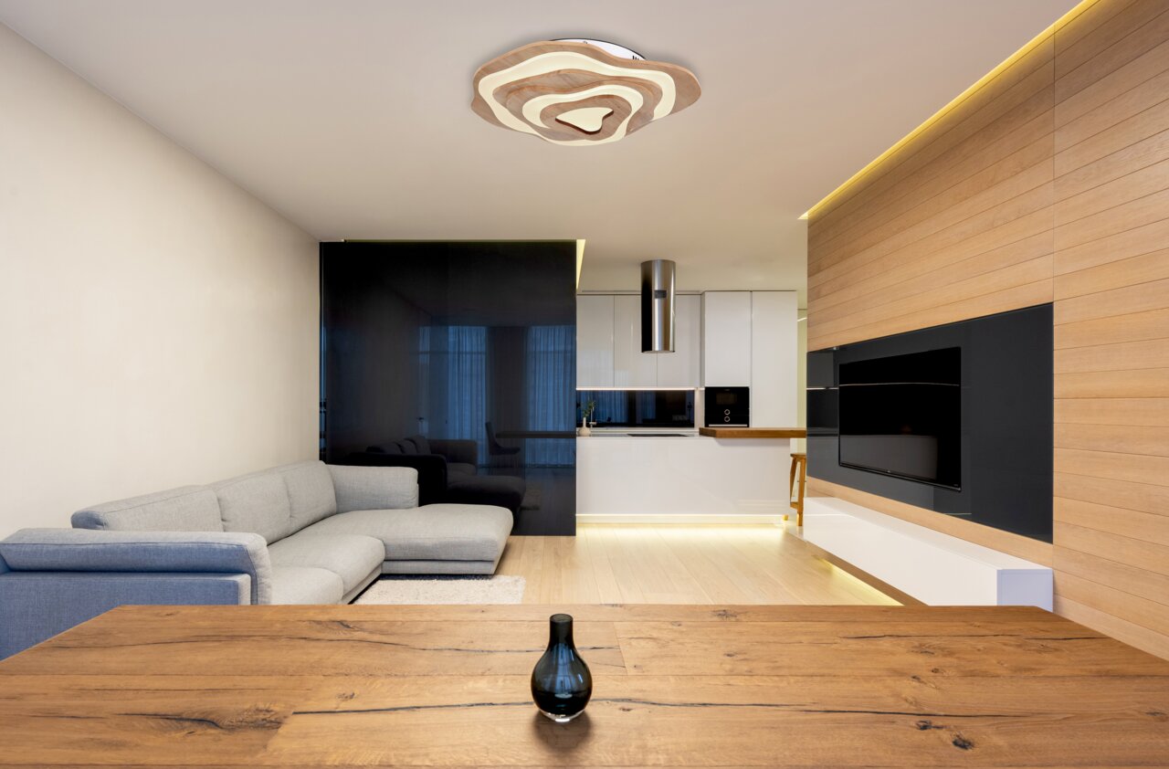 Moderne Deckenleuchte in einem stilvollen Wohnzimmer, aus der Perspektive eines Esstisches fotografiert.