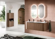 Modernes Badezimmer mit wandhängendem Doppelwaschtisch aus Holzdekor, weißer Doppelwaschplatte und schwarzen Armaturen vor roséfarbenen Fliesen sowie zwei ovalen, hinterleuchteten Spiegeln; Perspektive: frontale Ansicht leicht von links.