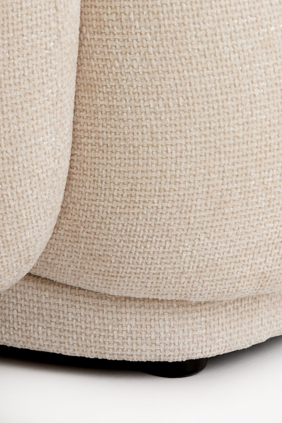 Nahaufnahme eines beigen, strukturierten Stoffes eines Stuhls, von der Seite betrachtet.