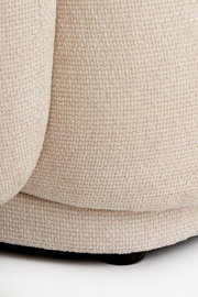 Nahaufnahme eines beigen, strukturierten Stoffes eines Stuhls, von der Seite betrachtet.