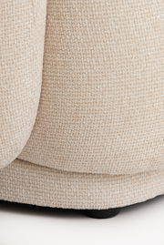 Nahaufnahme eines beigen, strukturierten Stoffes eines Stuhls, von der Seite betrachtet.