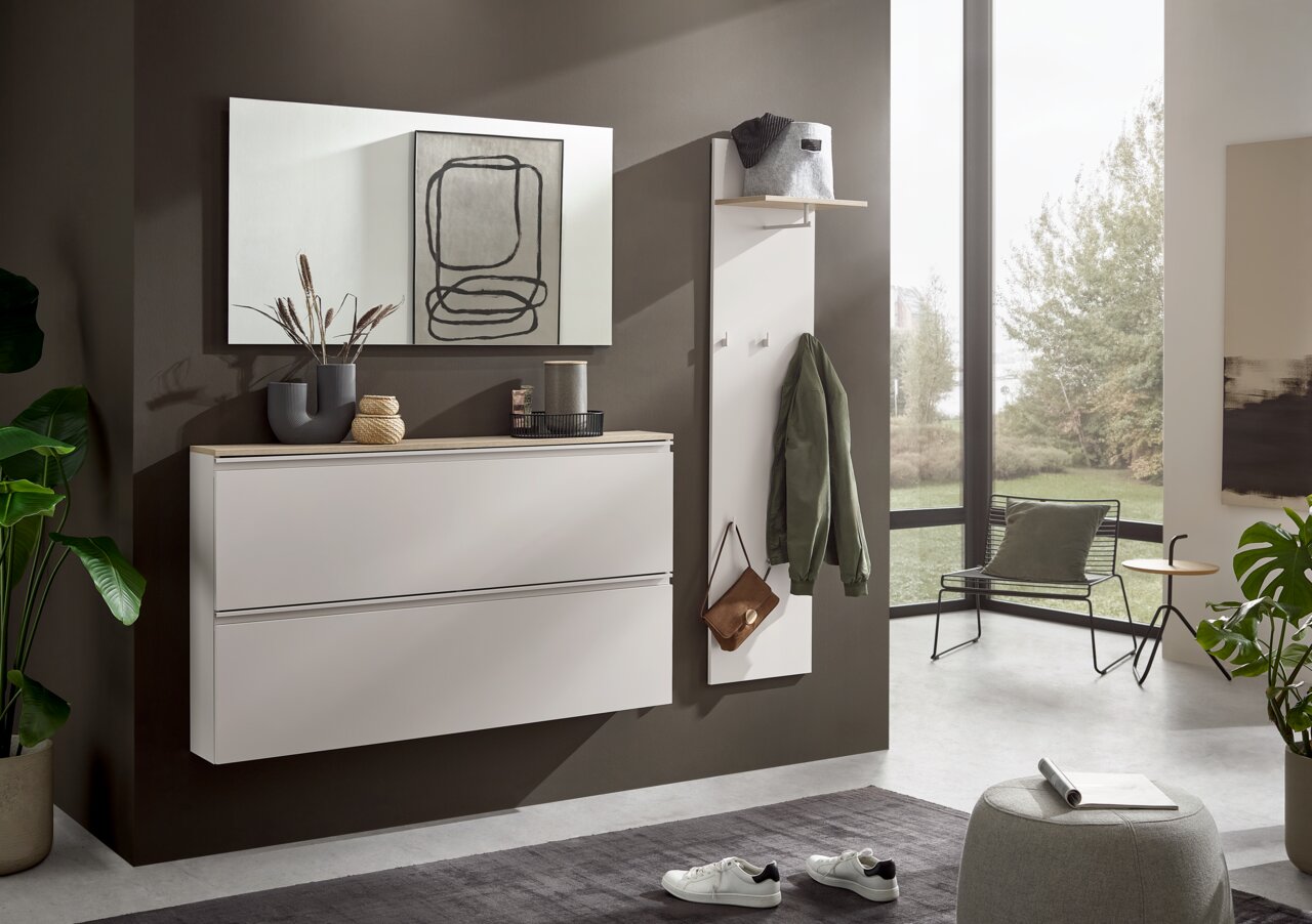 Voleo Hangende schoenenkast MILTON Moderne, aan de muur bevestigde halmeubelset in wit, met schoenenkast en kapstokpaneel met legplank en haken, in een lichte hal – vooraanzicht in licht schuin perspectief.