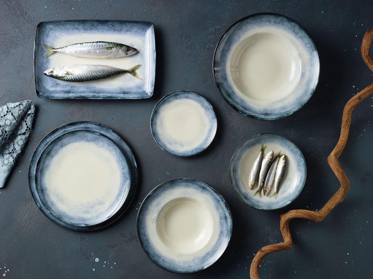 Arthur Krupp Tellerset Shade Sea 12-tlg. Vogelperspektive auf ein 12-teiliges Tellerset 'Shade Sea' mit blau-weißen Tellern und Schalen, dekoriert mit Fischen und einem Zweig.