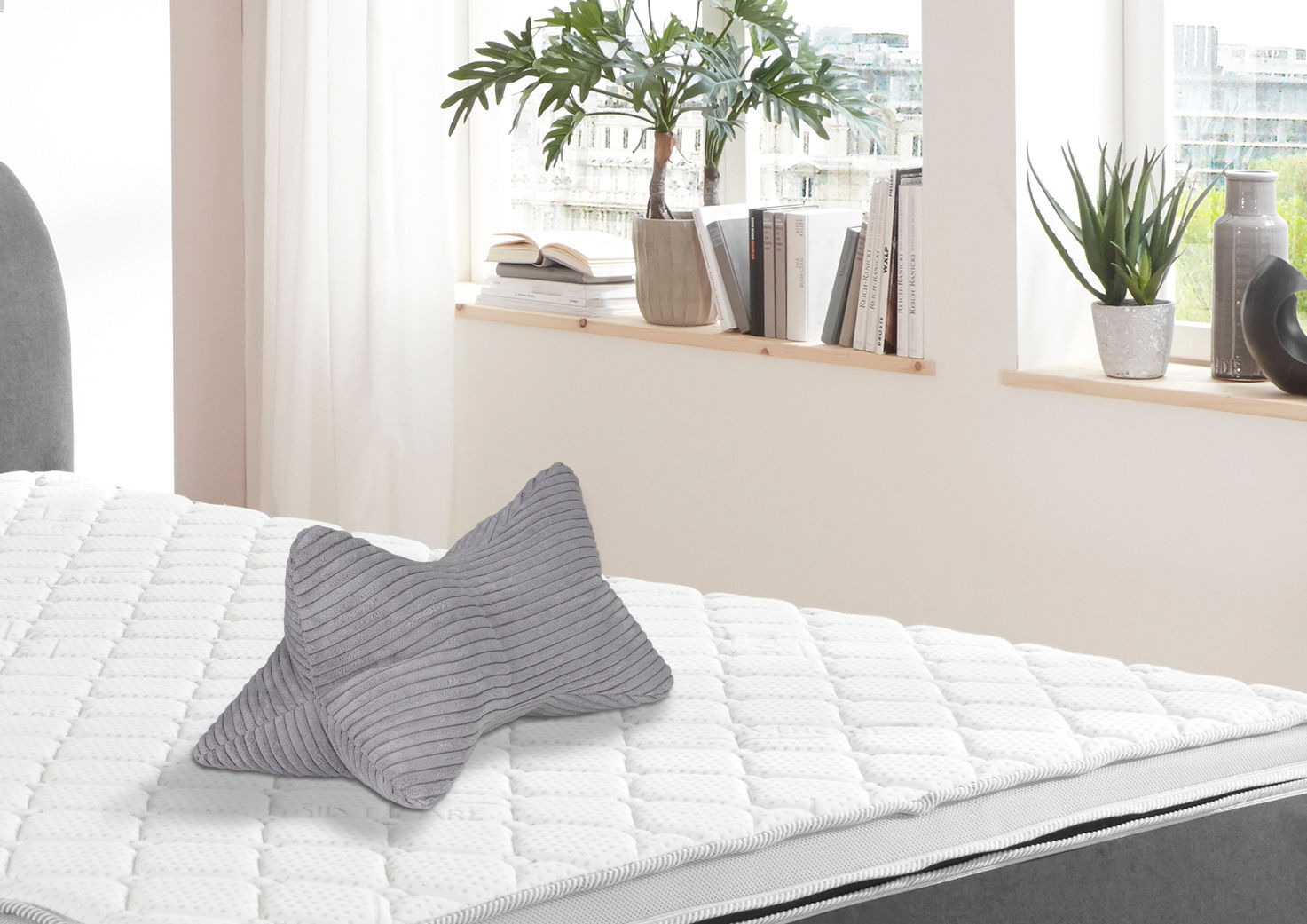 Grauer Leseknochen auf einem weißen Bett, seitliche Perspektive