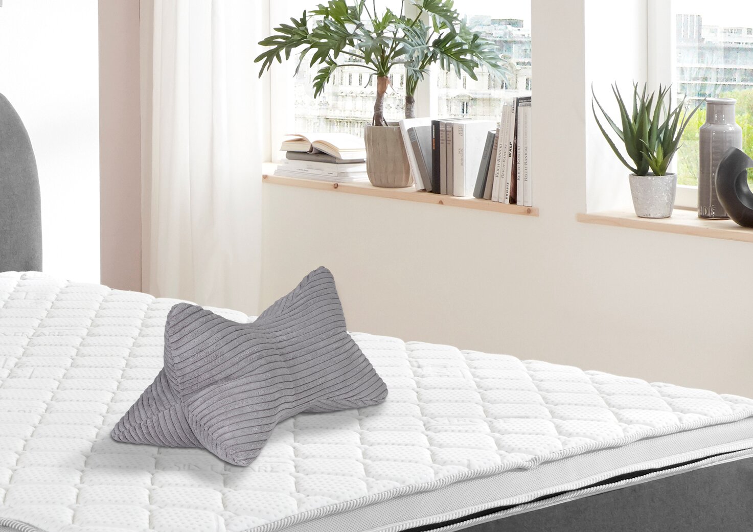 Grauer Leseknochen auf einem weißen Bett, seitliche Perspektive
