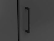 Nahaufnahme eines schwarzen Griffs an einer dunklen Eckkommode, seitliche Perspektive