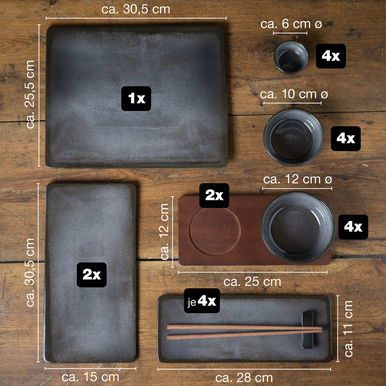 Vogelperspektive auf ein 29-teiliges Sushi-Set in Anthrazit, bestehend aus verschiedenen rechteckigen und runden Tellern, Schalen und Essstäbchen auf einem Holztisch.