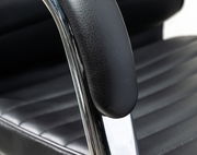 Nahaufnahme eines schwarzen Schwingstuhls mit gepolstertem Sitz und Armlehne aus Leder, seitliche Perspektive