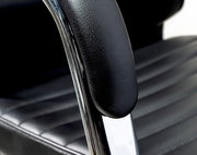 Nahaufnahme eines schwarzen Schwingstuhls mit gepolstertem Sitz und Armlehne aus Leder, seitliche Perspektive