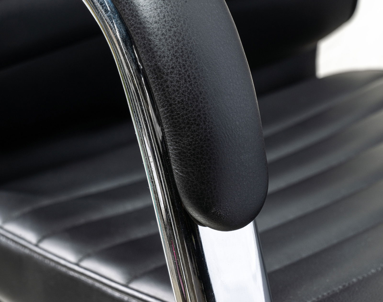 Nahaufnahme eines schwarzen Schwingstuhls mit gepolstertem Sitz und Armlehne aus Leder, seitliche Perspektive