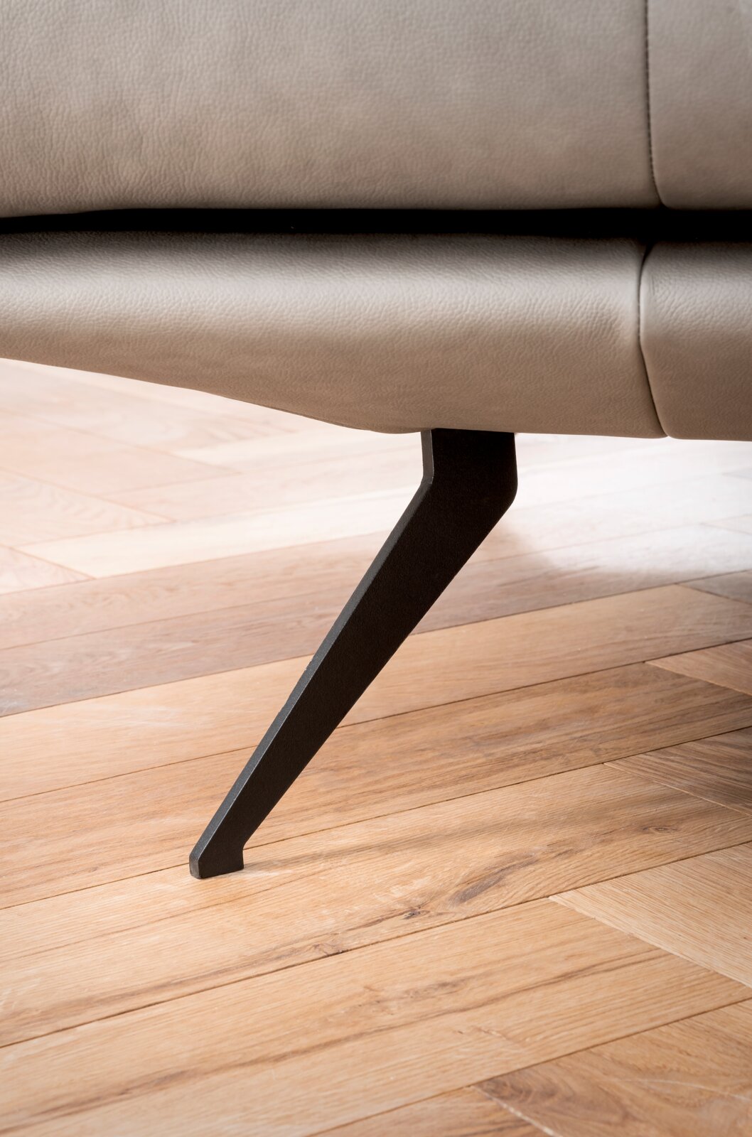 Close-up van een moderne metalen bankpoot op een houten vloer, zijaanzicht