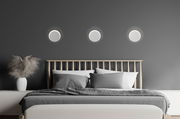 Moderne LED-Wandleuchten über einem Bett in einem stilvollen Schlafzimmer, frontal betrachtet.
