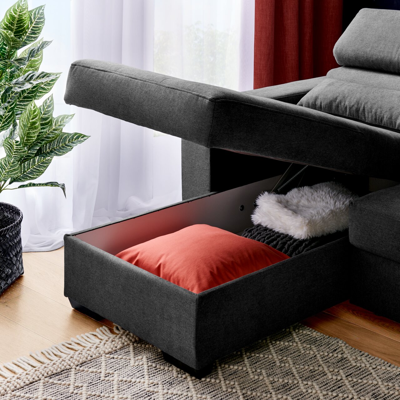 Graue Rundecke mit Stauraum, geöffnet, mit Kissen und Decke, seitliche Perspektive