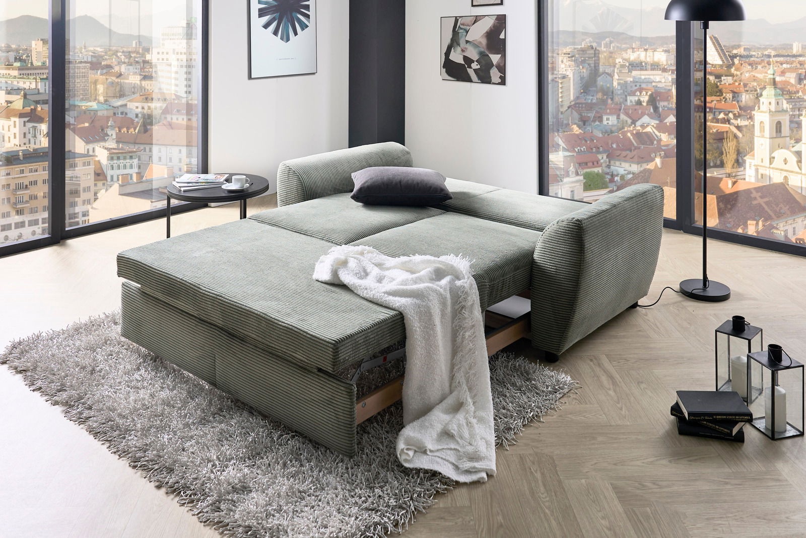 Funktionssofa in einem modernen Wohnzimmer mit Stadtblick, aus der Perspektive von vorne links fotografiert.