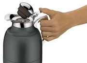 Nahaufnahme einer Hand, die den Griff einer grauen Isolierkanne Juwel hält, mit geöffnetem Deckel.