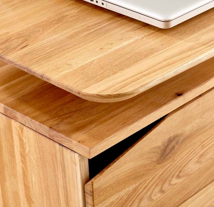 Nahaufnahme eines Schreibtisches aus Holz mit abgerundeten Kanten und einer Schublade, von oben fotografiert.