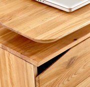 Nahaufnahme eines Schreibtisches aus Holz mit abgerundeten Kanten und einer Schublade, von oben fotografiert.