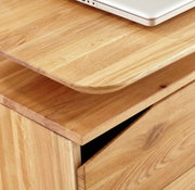 Close-up van een houten bureau met afgeronde hoeken en een lade, gefotografeerd van bovenaf.