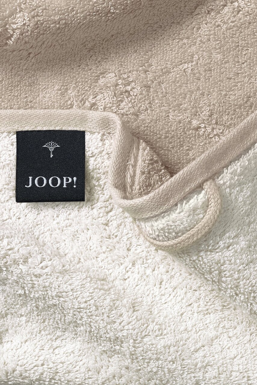Nahaufnahme eines beigen Gästetuchs mit einem schwarzen Joop!-Etikett.