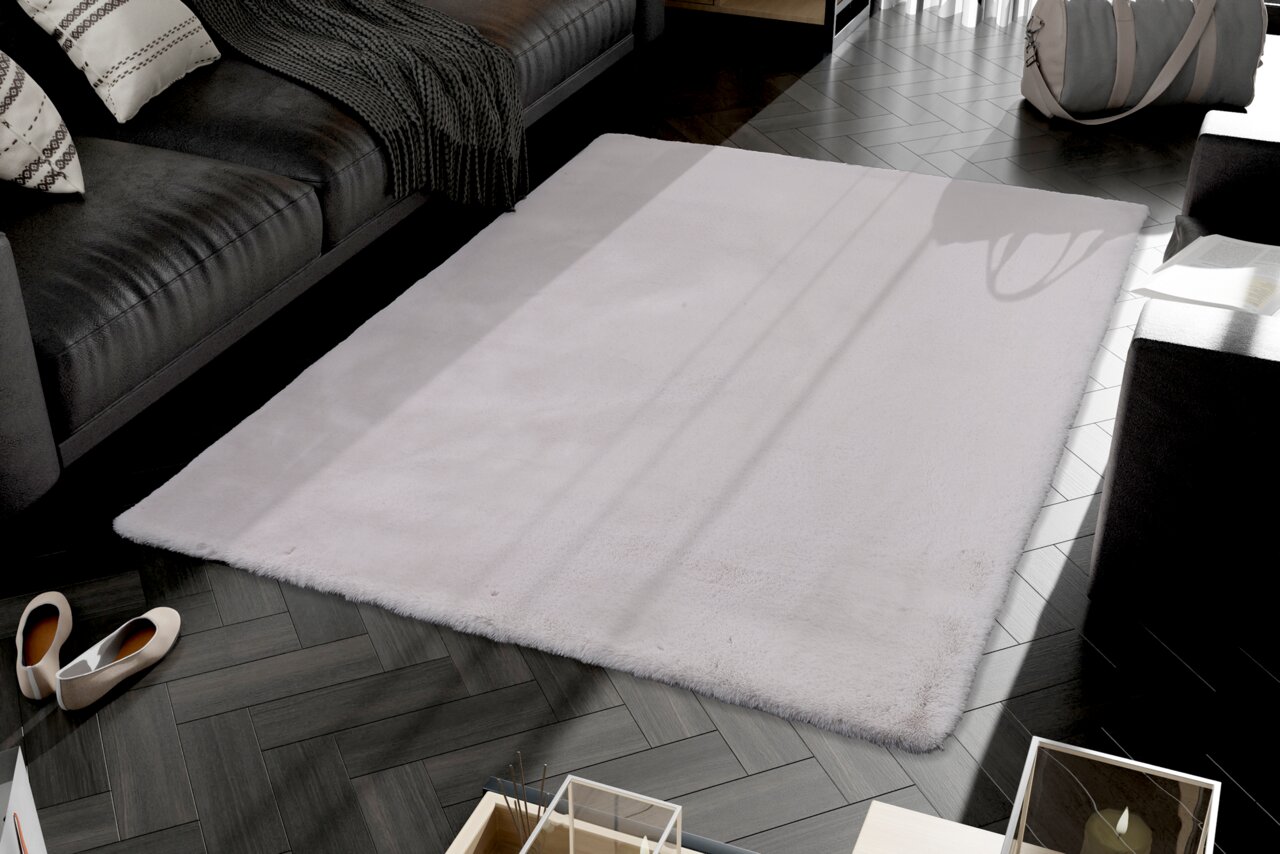 Fellteppich in einem modernen Wohnzimmer, aus der Vogelperspektive fotografiert, mit einem grauen Sofa und dekorativen Kissen im Hintergrund.