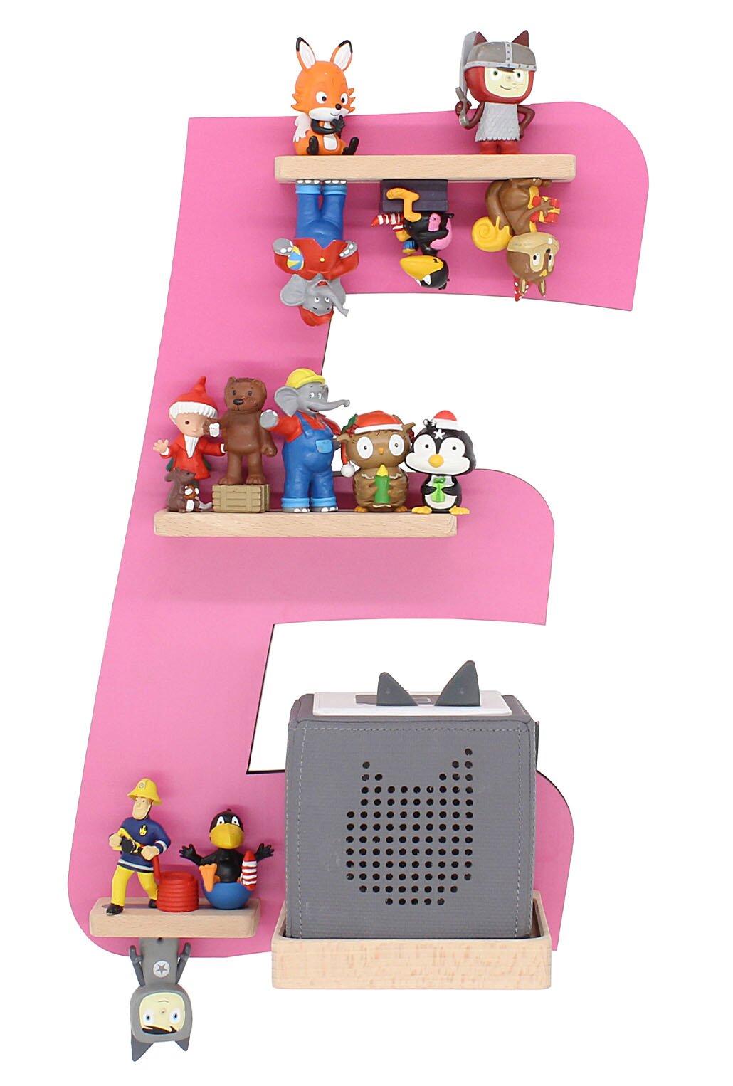 Frontalansicht: Große rosafarbene Dekoration in Form des Buchstabens E mit mehreren kleinen Spielfiguren auf Holzleisten unten ein grauer Würfel-Lautsprecher mit Katzenmotiv auf Holzsockel.
