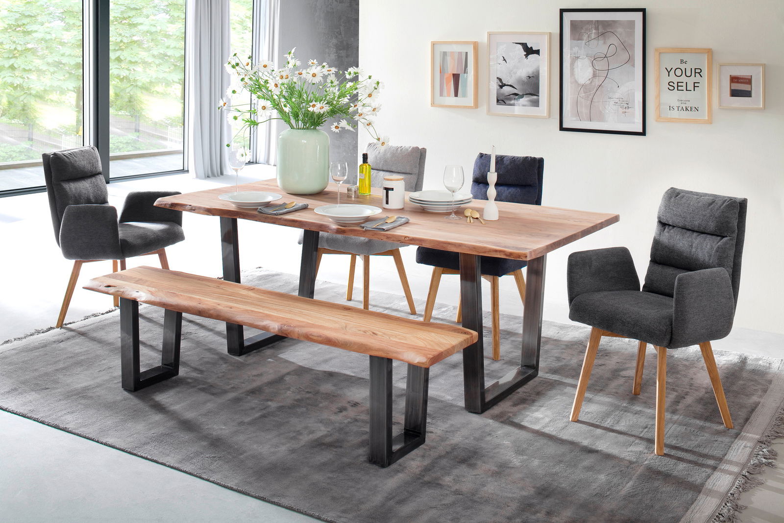 Moderner Essbereich mit einem großen Holztisch und passender Bank, umgeben von grauen Polsterstühlen, aus der Perspektive von vorne fotografiert.