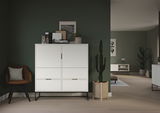 Weißes Highboard mit sechs Fächern, dekoriert mit Pflanzen und Bildern, in einem modernen Wohnzimmer mit grüner Wand, aus frontaler Perspektive.
