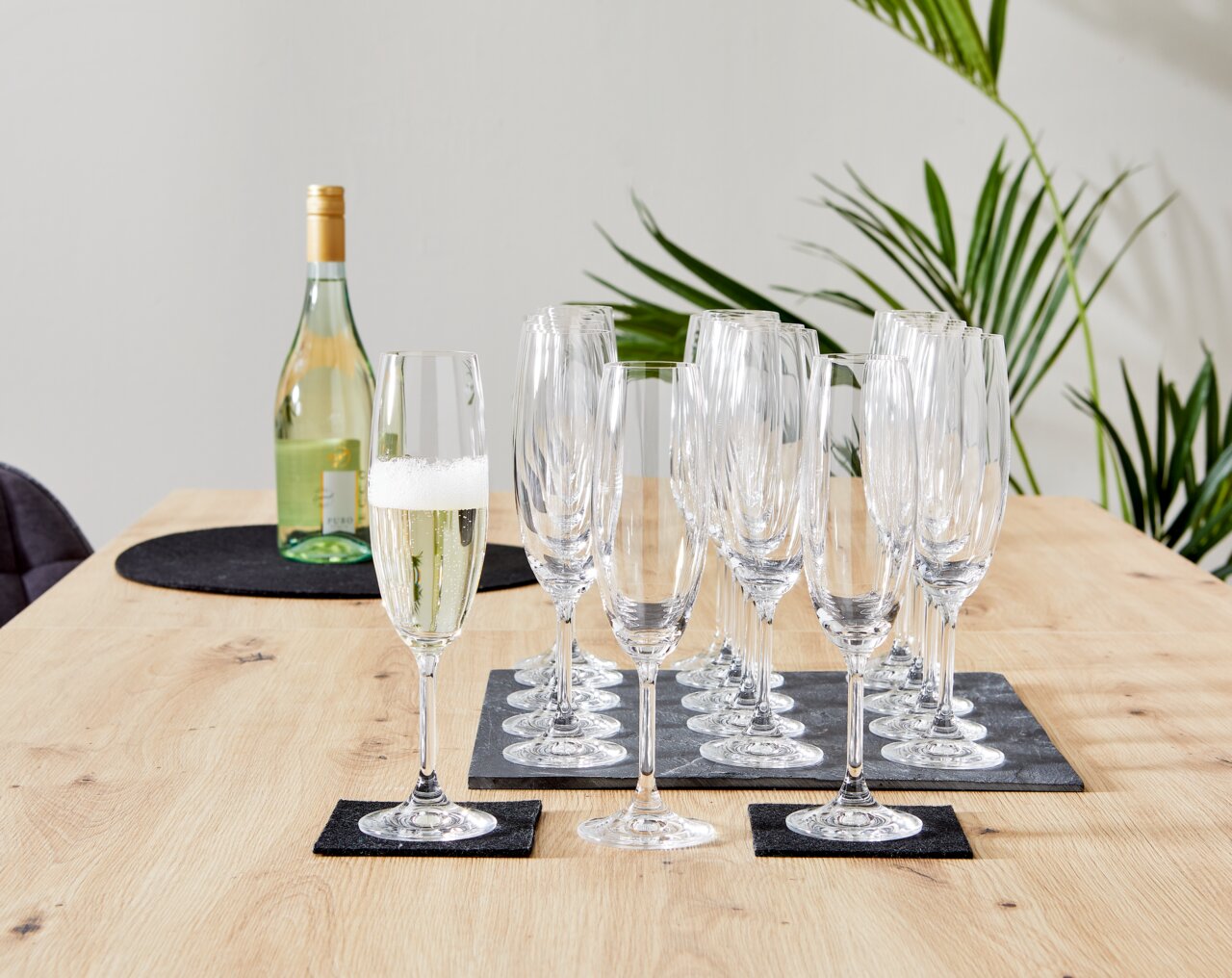 Novel Set champagneglazen, 18-delig Set van 18 champagneglazen op een houten tafel, zijaanzicht, met een fles champagne op de achtergrond.