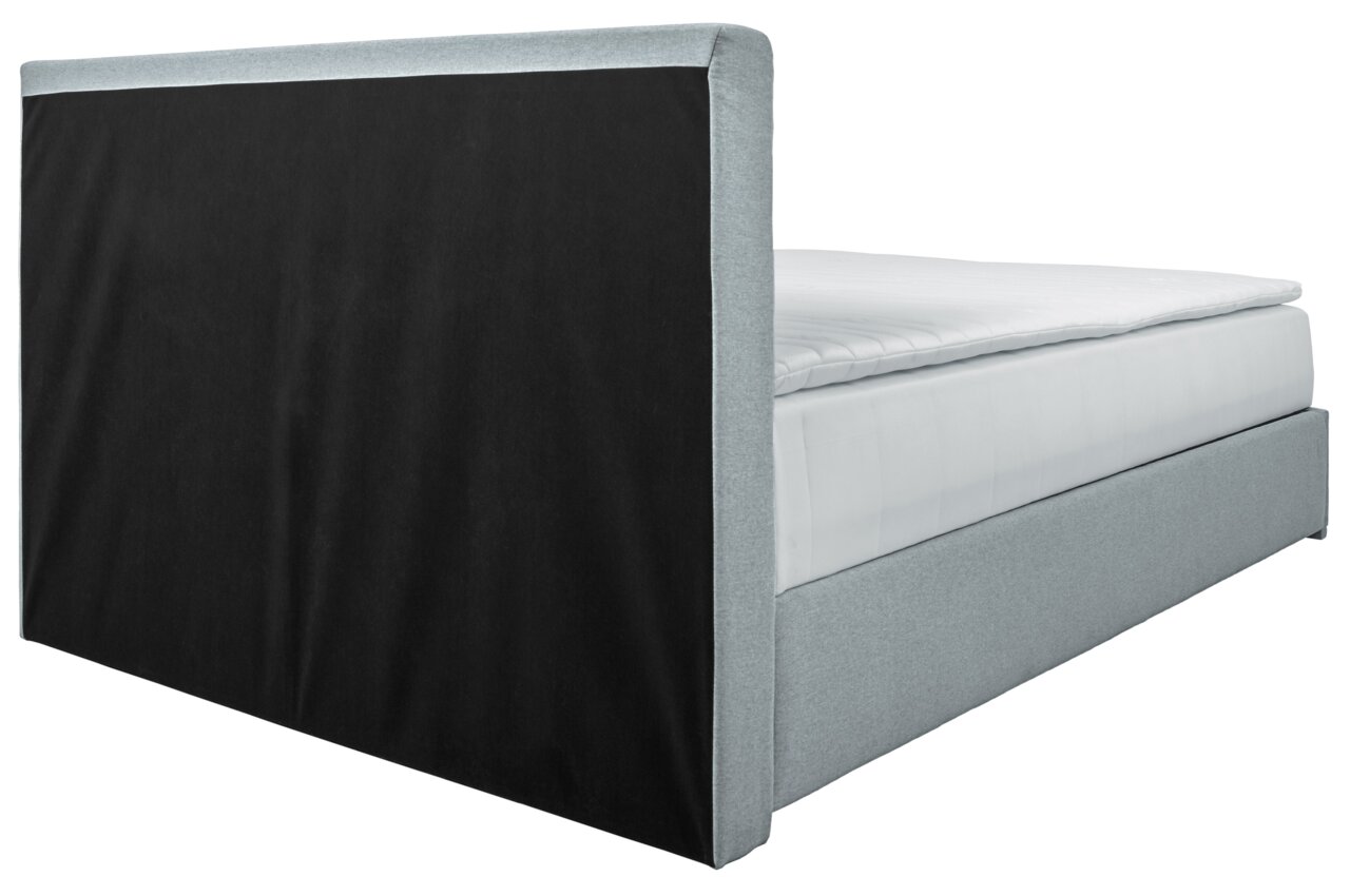 Boxbed 140 in zijaanzicht met grijze stoffen bekleding en een zwart hoofdeinde.