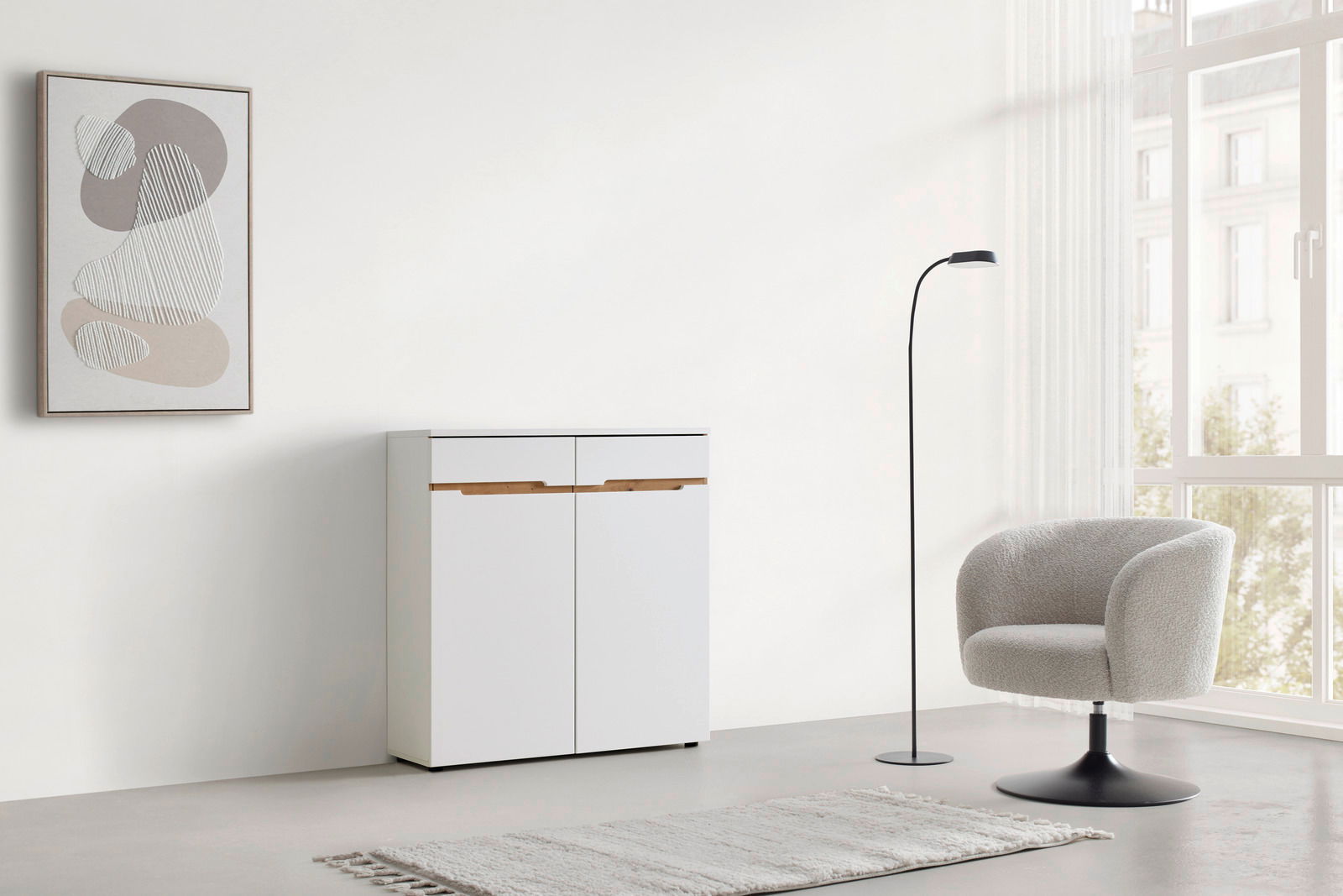 Moderne weiße Kommode mit Holzgriffen, frontal abgebildet in einem minimalistischen Raum mit einem Sessel, Stehlampe und abstraktem Wandbild.