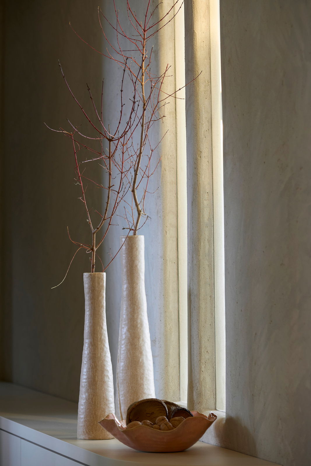 Light&Living Vase SETIMMO 45cm Zwei hohe, schlanke Vasen mit Zweigen, auf einem Tisch vor einem Fenster, seitliche Perspektive.